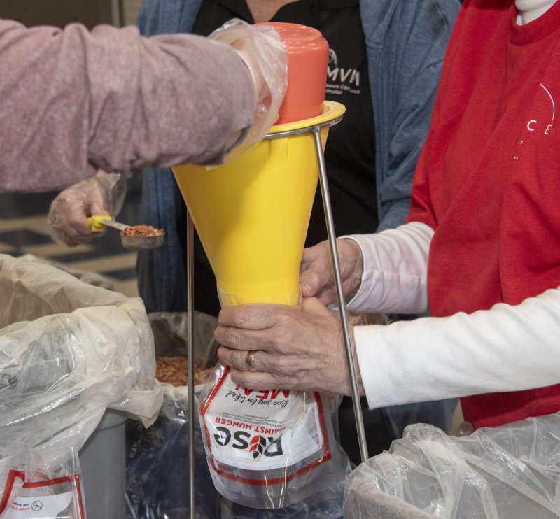 With the mantra “rice goes last,” volunteers fill the bags.